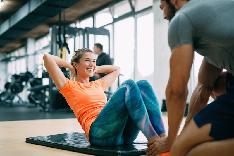 Woman doing situps with personal trainer